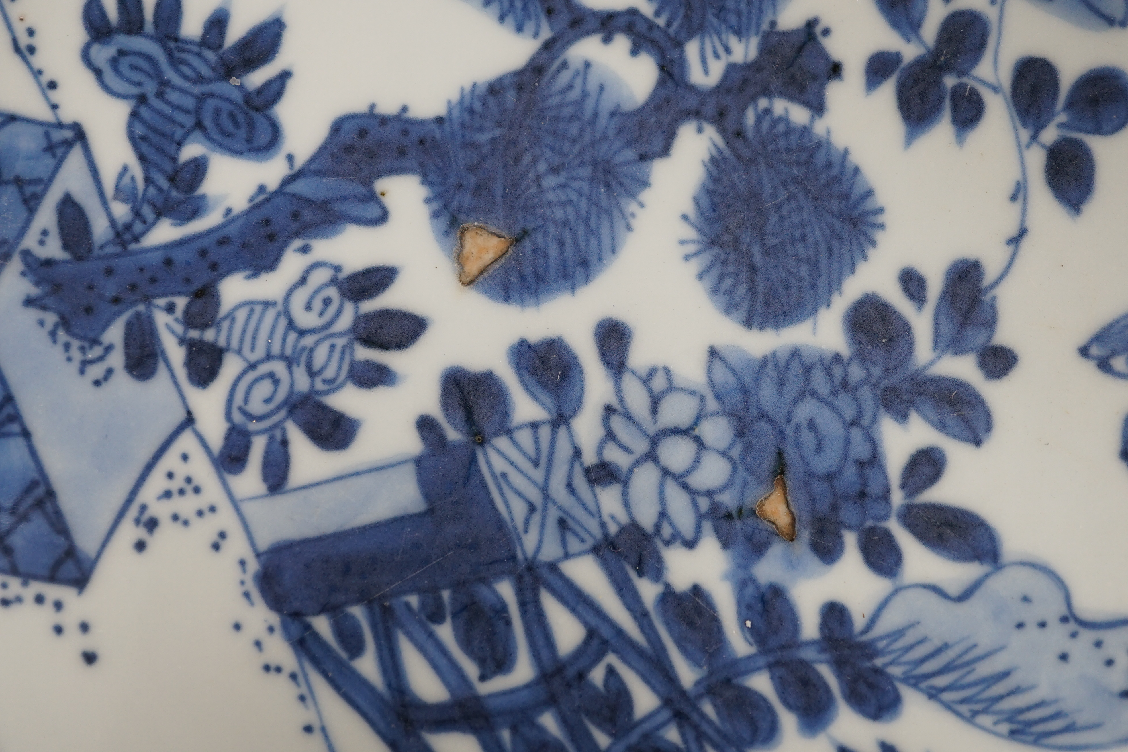 A pair of Chinese blue and white ‘garden’ dishes, Kangxi period, fritting and glaze chips